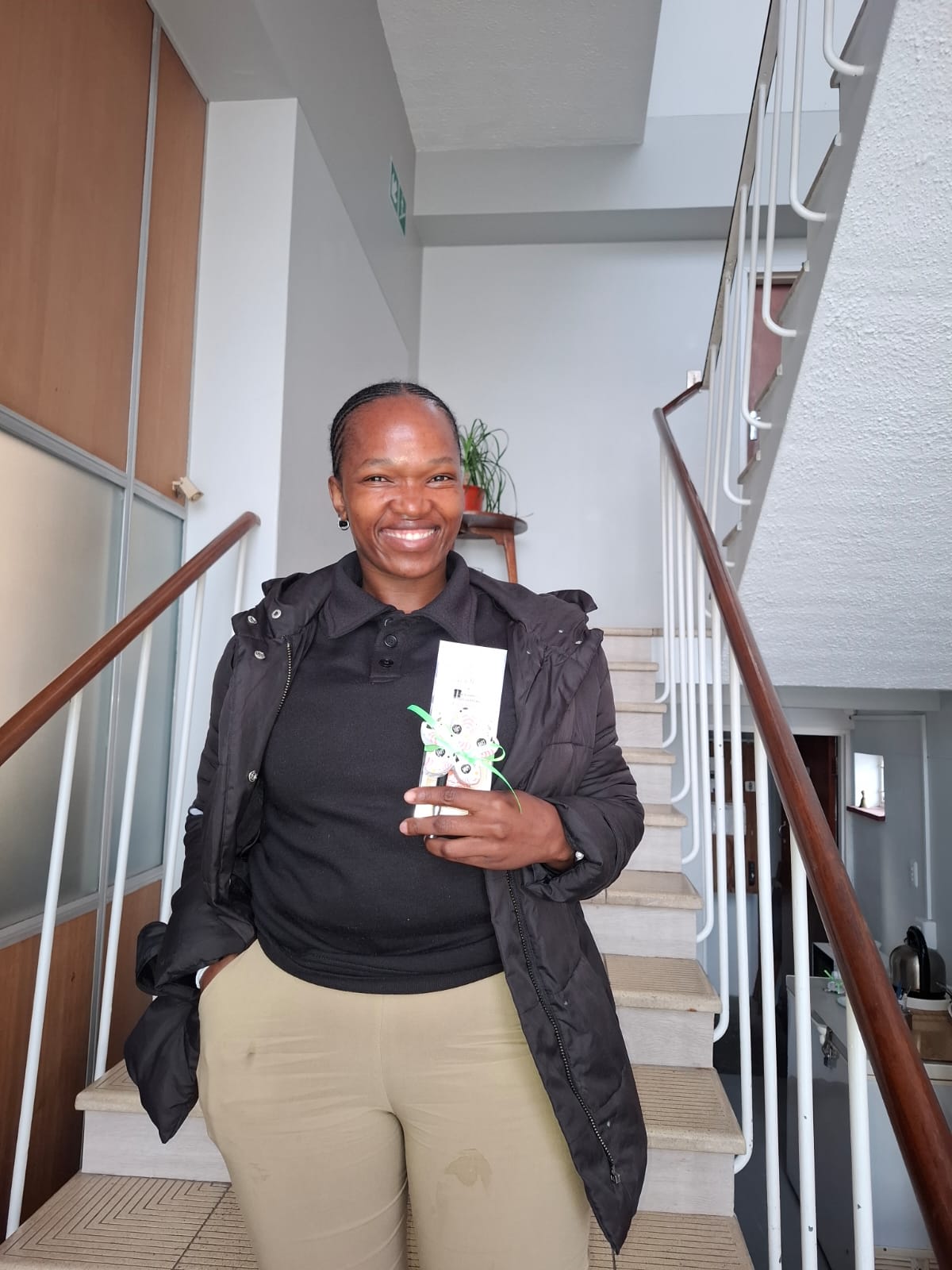 A team member smiling on the stairwell, holding her Women's Day thank-you card.